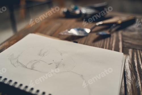 Preview: Notebook with face sketch on wooden table