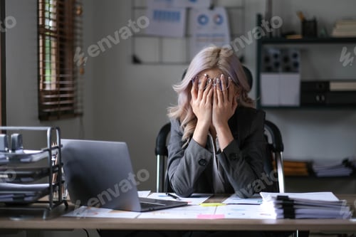 Preview: Tired and stressed young asian woman sitting at her working place..