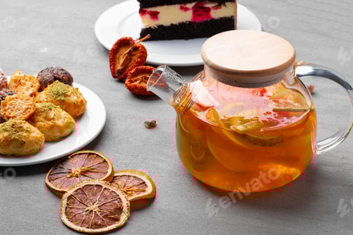 Preview: Glass teapot with fruit tea and cookies on gray background