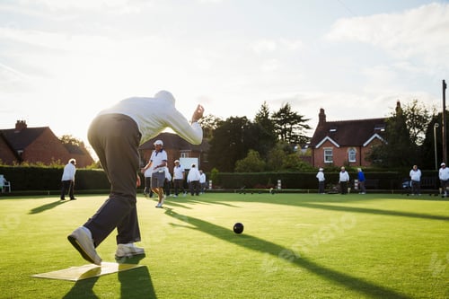 Preview: A lawn bowls player standing on a small yellow mat preparing to deliver a bowl down the green, the