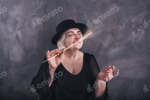 Preview: older woman in black clothes and a black hat on a solid background of a dark gray concrete