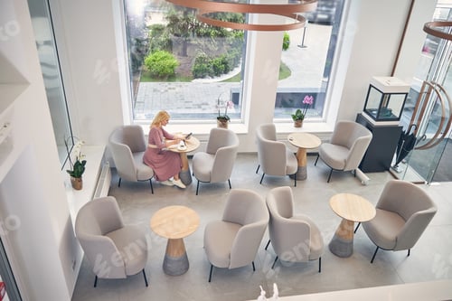 Preview: Busy female person sitting alone in cafe
