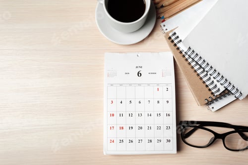 Preview: Calendar on a desk with coffee, notebooks, and glasses shows planning for June