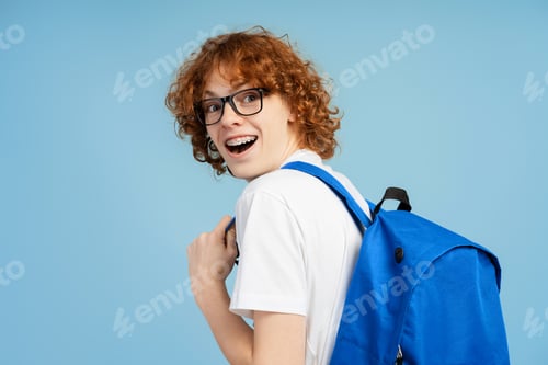 Preview: Excited red head teen with braces, equipped with eyewear and backpack, looking over his shoulder