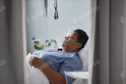 Preview: African American woman laying on bed in hospital room with oxygen support mask