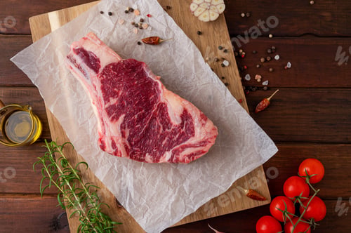 Preview: Raw fresh meat steak on a wooden board with ingredients for cooking. Ribeye steak. Top view.