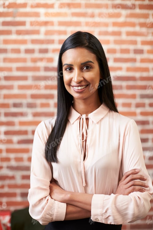 Preview: Portrait Of Smiling Young Businesswoman Standing Against Brick Wall In Modern Office