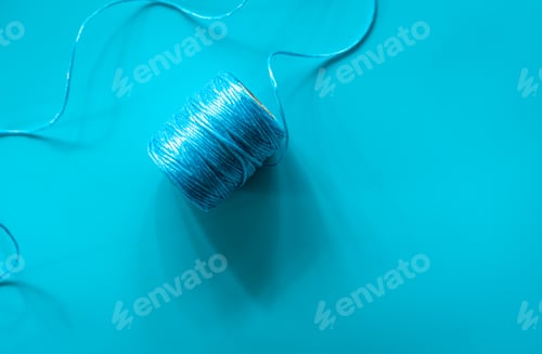 Preview: A ball of blue threads on a blue background, flat lay.