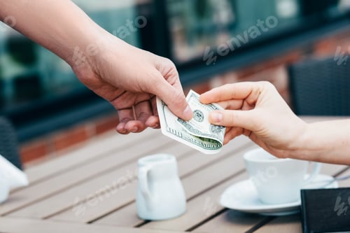 Preview: woman paying with dollars notes in a cafe, close-up