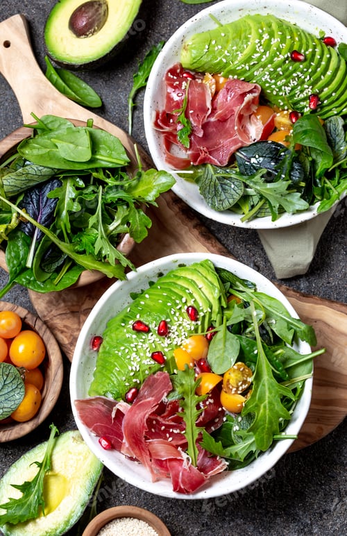Preview: Low carbs bowl. Fresh salad with green spinach, rucola, avocado an ham serrano in white bowl, gray