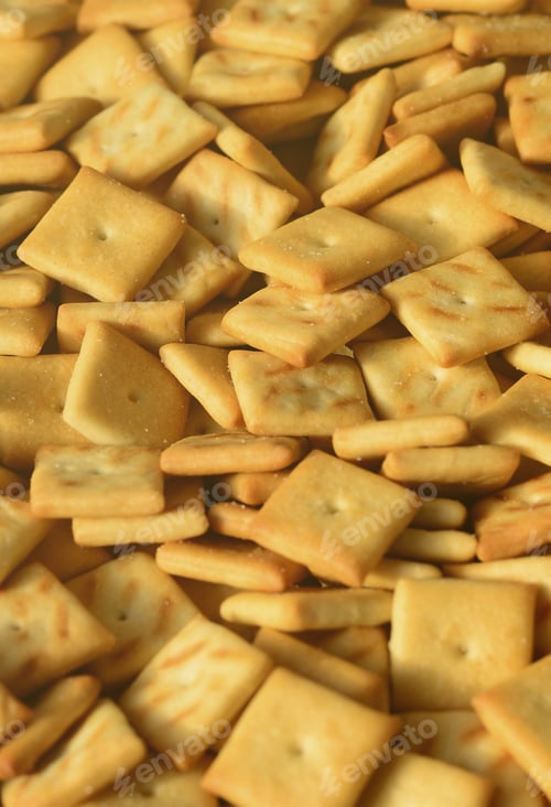 Preview: A lot of small cookies are square shaped. A pattern of a yellow salt cracker. Background im