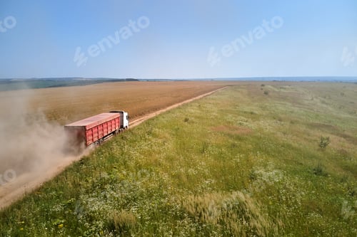 Preview: Aerial view of lorry cargo truck driving on dirt road between agricultural wheat fields.