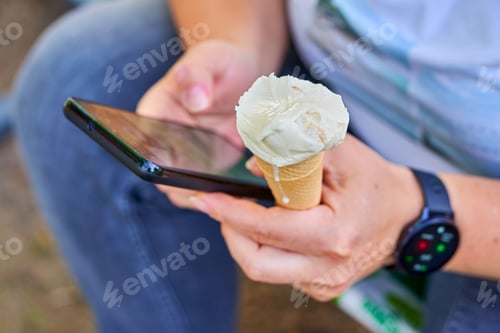 Preview: Closeup of male hands holding ice cream and phone in the garden