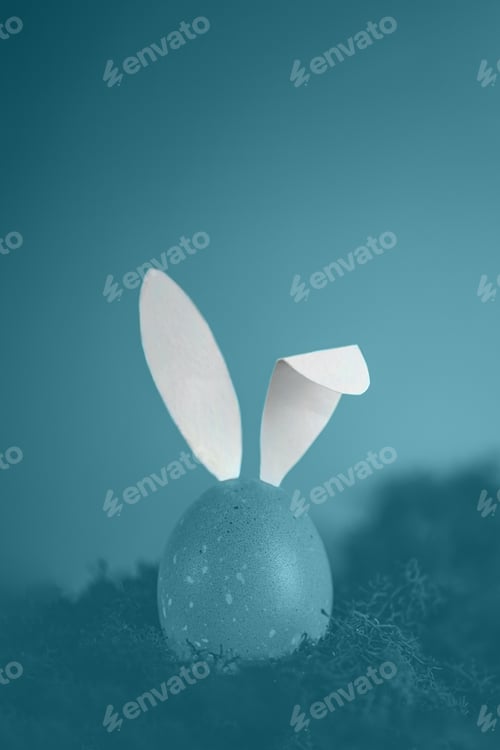 Preview: Tinted in blue photo, easter egg with white rabbit ears. creative minimalistic photo