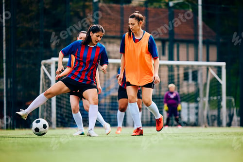 Preview: Young sportswoman trying to pass her rival during soccer practice on playing field.