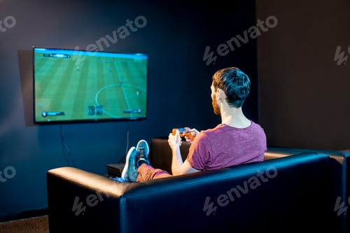 Preview: Man playing football game with gaming console