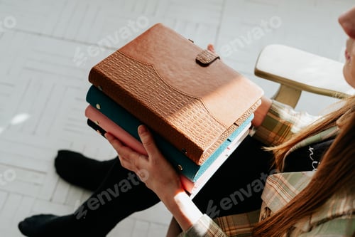 Preview: Cropped picture of young woman's hands holding stack of notebooks. Girl holds a pile of notepads