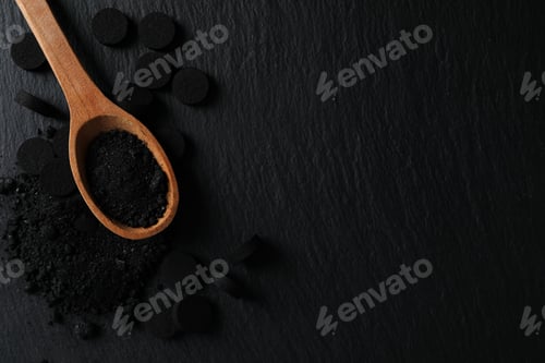 Preview: Activated charcoal powder in a wooden spoon on a dark background