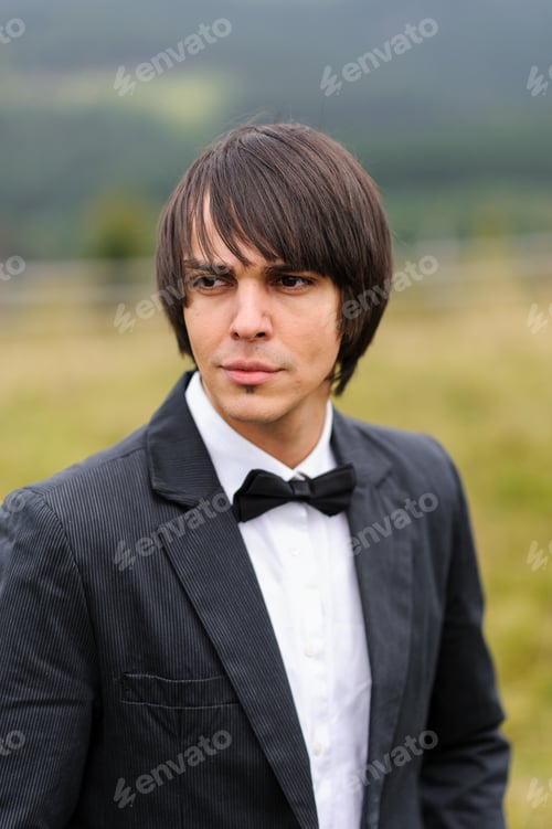 Preview: Portrait of the groom in a suit. Shot in the mountains.
