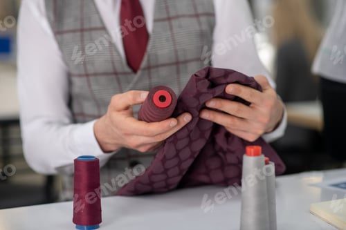 Preview: Hands of male tailor holding cloth and spool