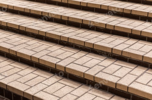Preview: Beige tiles of different shapes on the steps of concrete staircase, diagonal view