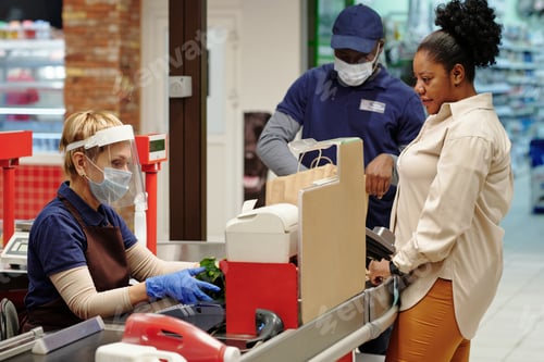 Preview: Cashier scanning food products while service staff putting them into paperbag