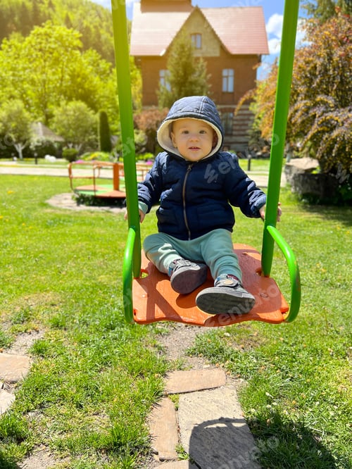 Preview: A cute boy of one and a half years rides on a swing. Backyard of the house. Children's entertainment