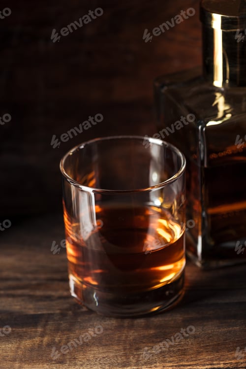 Preview: close-up view of glass of bourbon and bottle on wooden table
