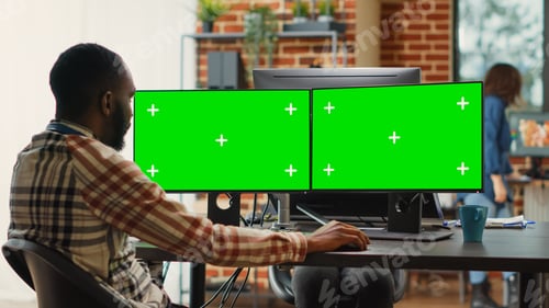 Preview: African american man analyzing greenscreen on multi monitors