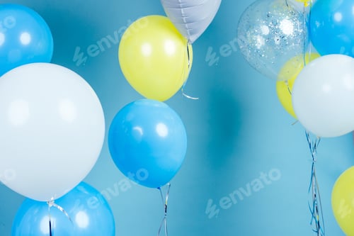 Preview: yellow, blue and white balloons on blue wall background copy space.