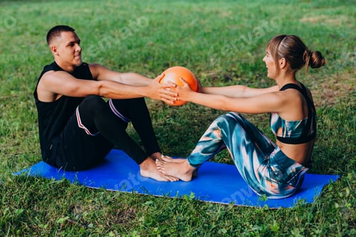 Preview: Man and woman together doing exercise with a ball outdoor