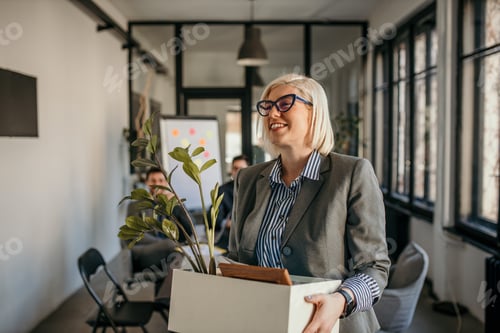 Preview: Smiling businesswoman leaving office carrying box with belongings
