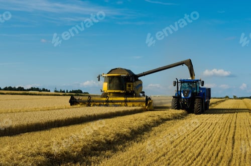 Preview: Combine harvester and tractor harvesting a crop in a field in summer.