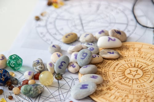Preview: Numerology stones with numbers on wooden zodiac wheel and natal charts background
