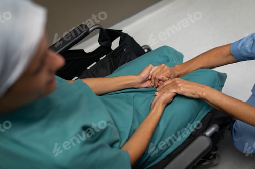 Preview: Female patient in a wheelchair holding the hands of her surgeon in the hospital corridor