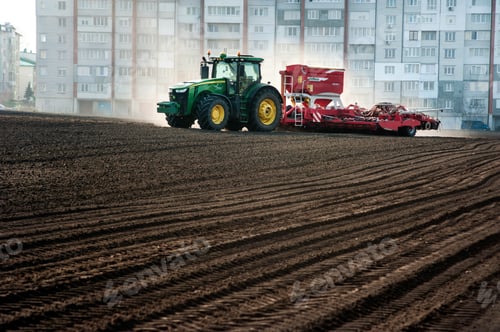 Preview: Farmers fertilize and sow, tractor with seeder with fertilizer at the field within the city