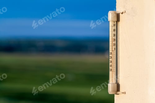Preview: Thermometer celsius showing warm temperature on blurred green background. Weather forecast concept