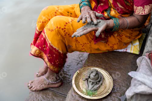 Preview: Indian woman applying mud to her hands performing a ritual
