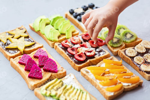 Preview: Variety of sandwiches with fresh berries and fruits and hand on gray concrete background.