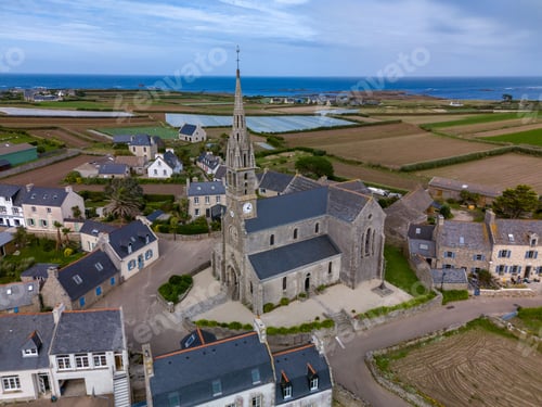 Preview: Aerial view of a village with a historic stone church and coastline.