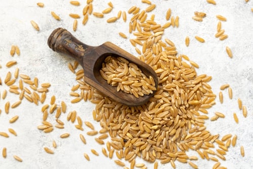 Preview: Wooden scoop of raw dry rye grain on white table top view