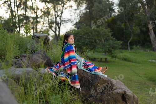 Preview: Little Mexican girl wearing a large dress tucked in a serape in a rural location.