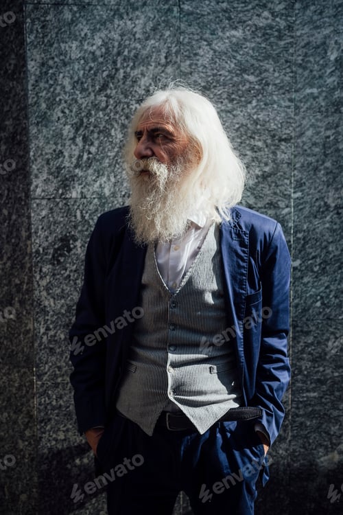 Preview: Senior businessman leaning against building wall