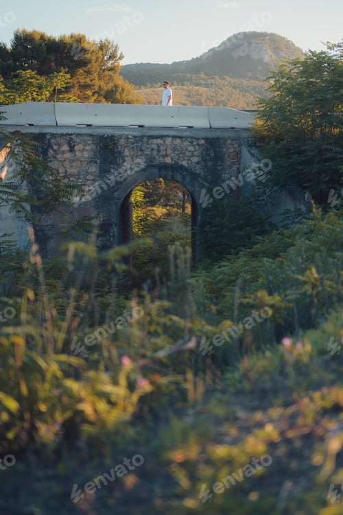 Preview: Latin man on bridge surrounded by nature at sunset