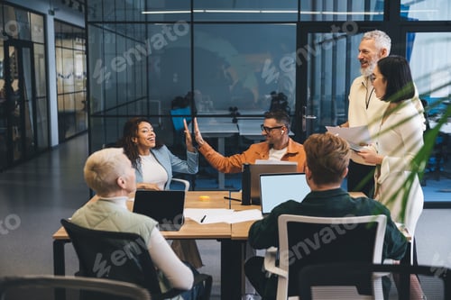 Preview: Cheerful colleagues working on computers in office