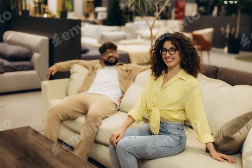Preview: Young couple relaxing on sofa in furniture showroom