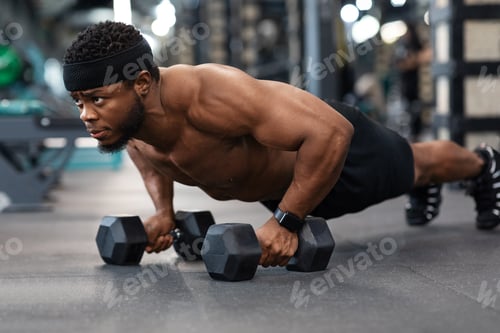 Preview: Concentrated black guy sportsman pushing up with dumbbells