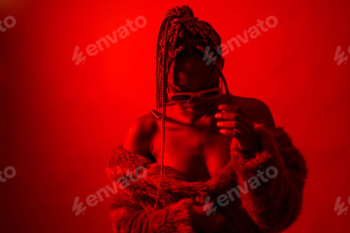 Preview: Attractive black ethnic woman with braids with red led lights, trap dancer wearing sunglasses