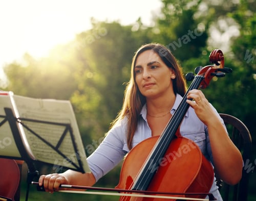 Preview: Cropped shot of a beautiful woman playing a cello in the backyard