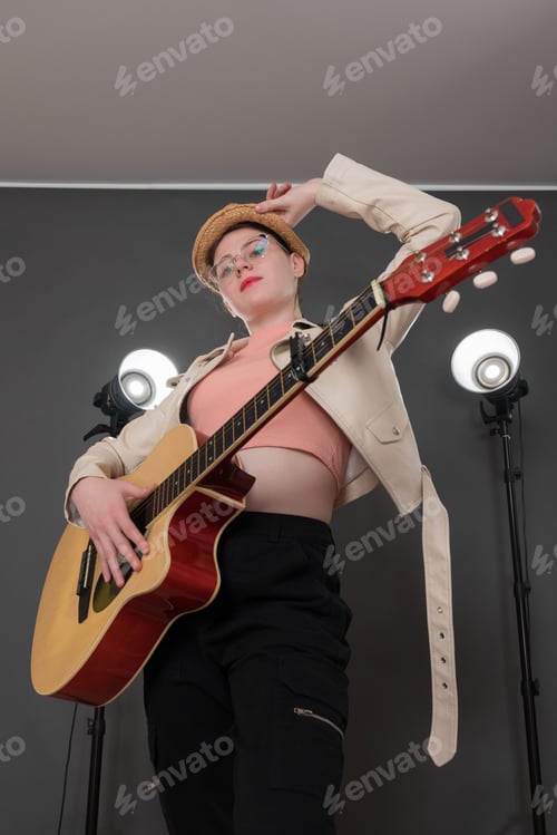 Preview: Portrait of confident female guitarist holding acoustic guitar, looking confidently at camera